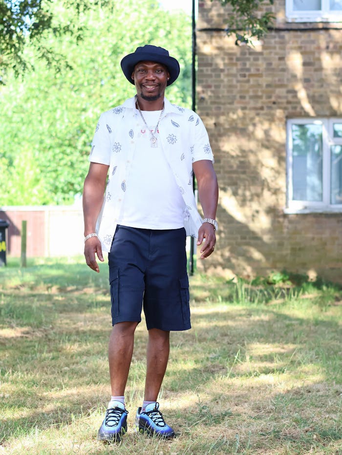 A cheerful man in summer clothes enjoys a sunny day outdoors, radiating happiness.